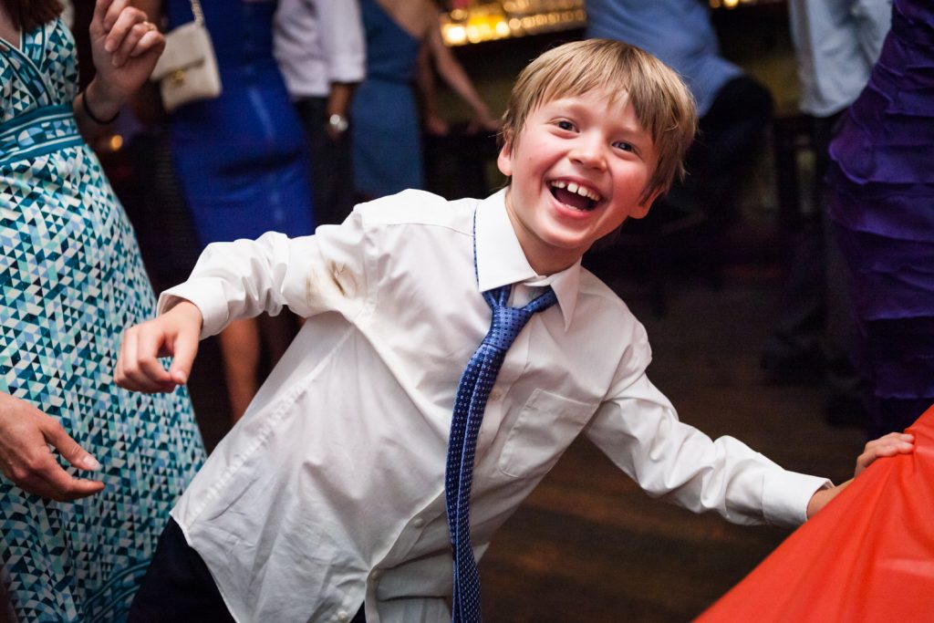 Young boy clowning around and wearing blue tie during Williamsburg wedding reception