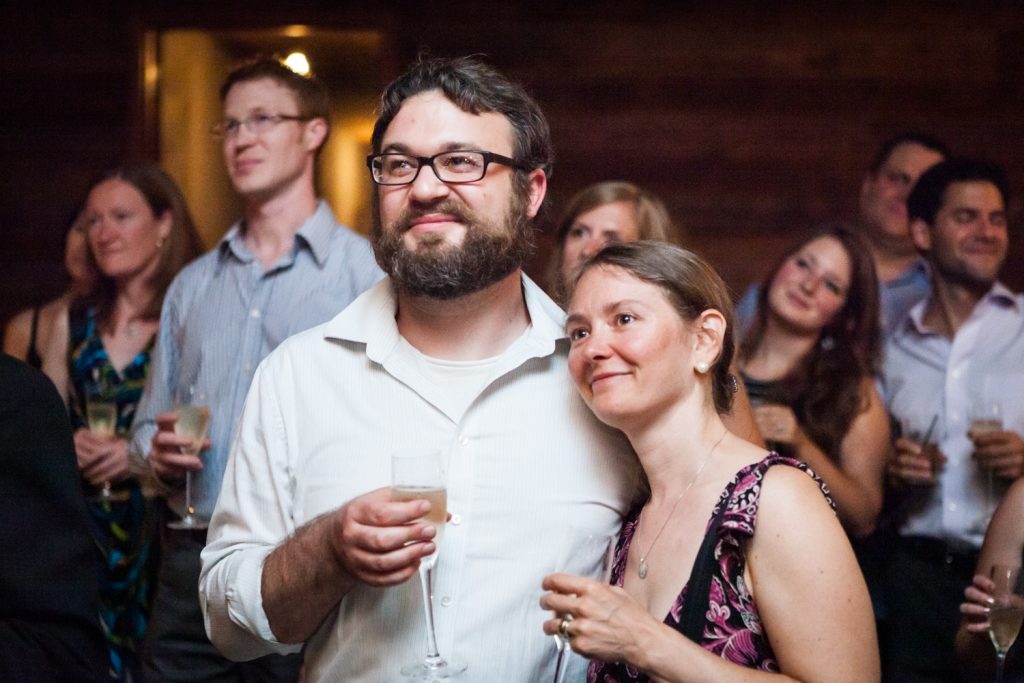 Couple holding glasses and listening to speeches during Williamsburg wedding reception