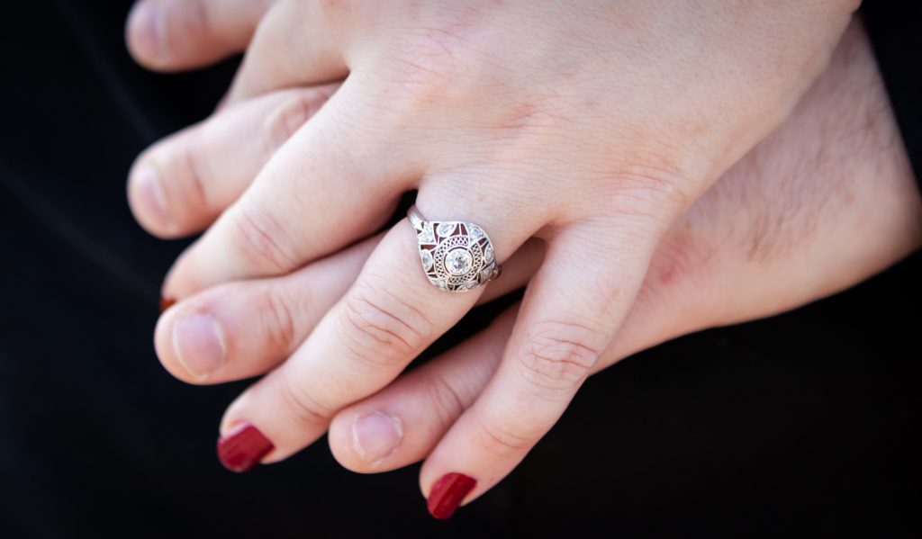 Close up of couple holding hand with woman wearing engagement ring