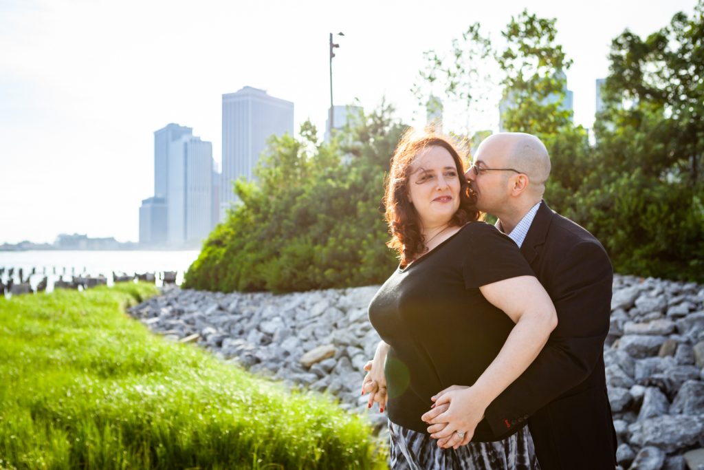 Man kissing woman on cheek during a Brooklyn Bridge Park engagement portrait session