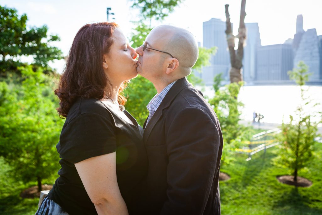 Couple kissing in middle of park during a Brooklyn Bridge Park engagement portrait session
