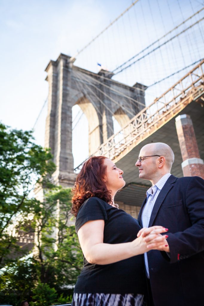 Couple at base of Brooklyn Bridge during a Brooklyn Bridge Park engagement portrait session