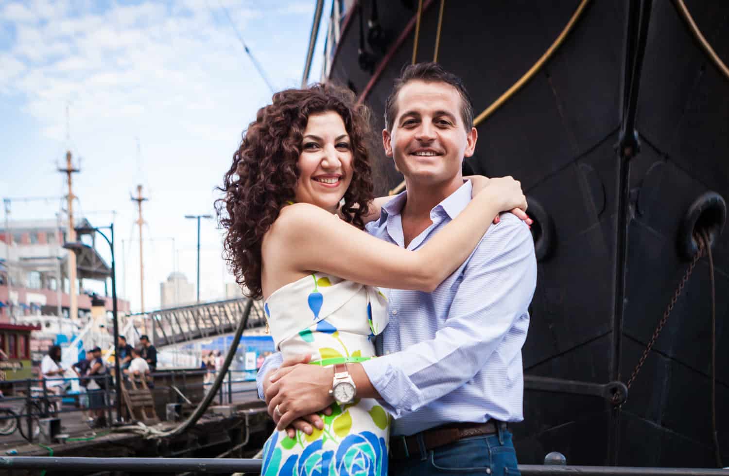 Financial District engagement photos of couple hugging in front of ship