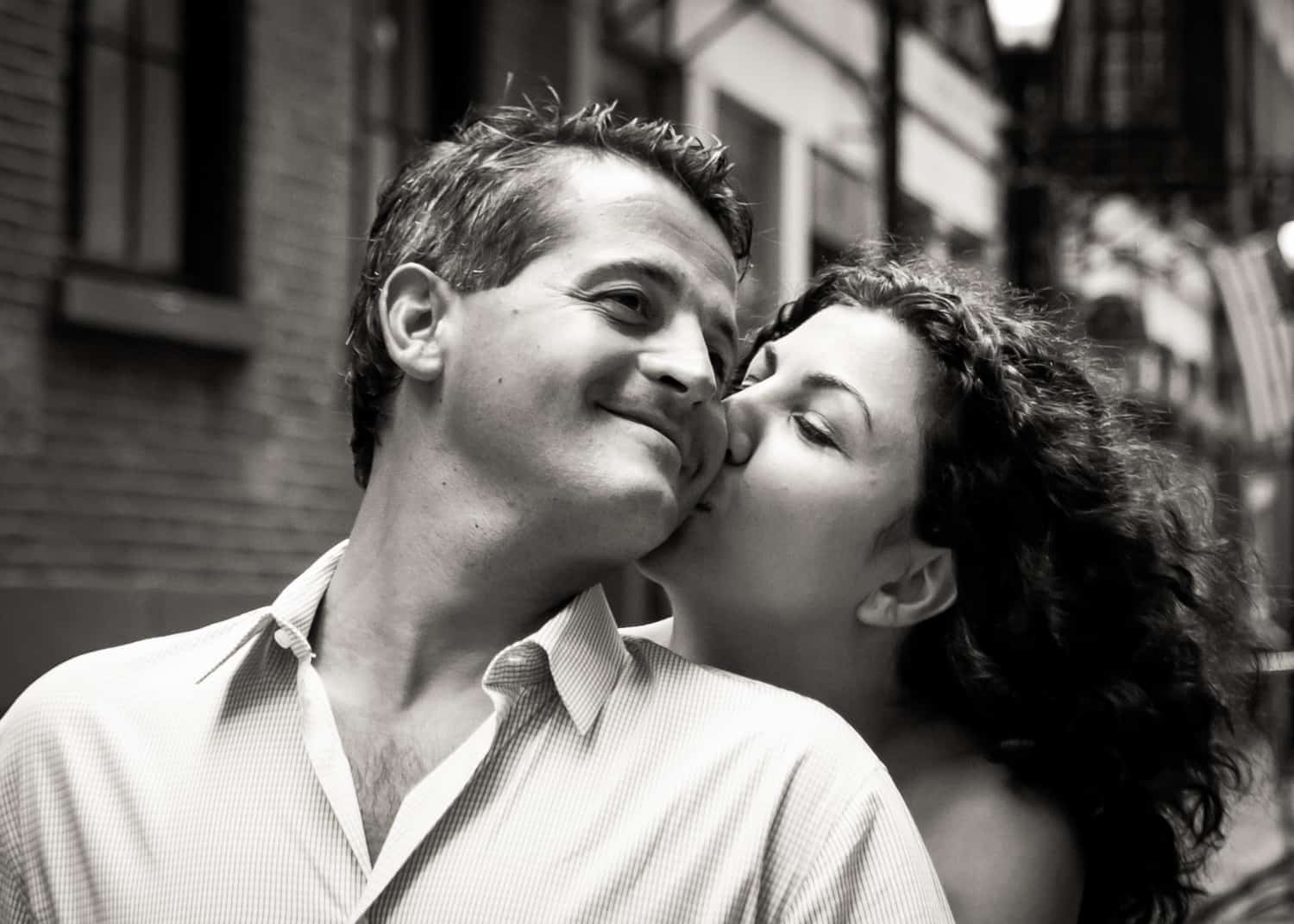 Black and white photo of woman kissing man on the cheek