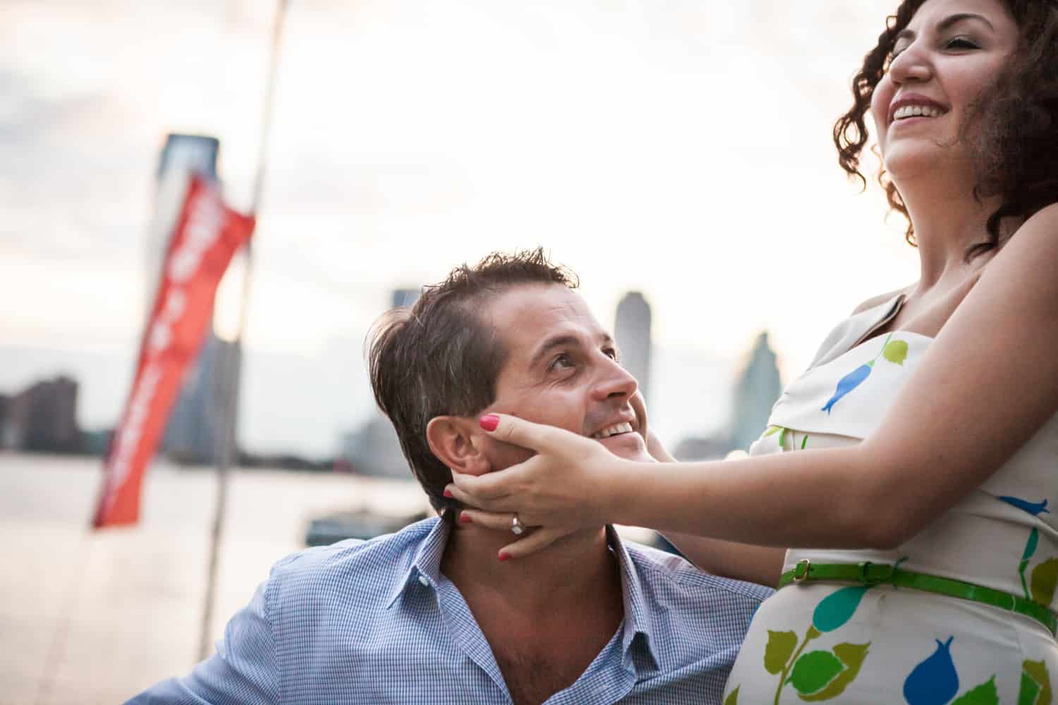 Woman touching man's face in front of NYC waterfront