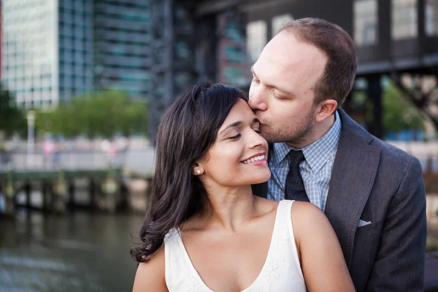 Man kissing woman on side of head at a Gantry Plaza State Park engagement shoot