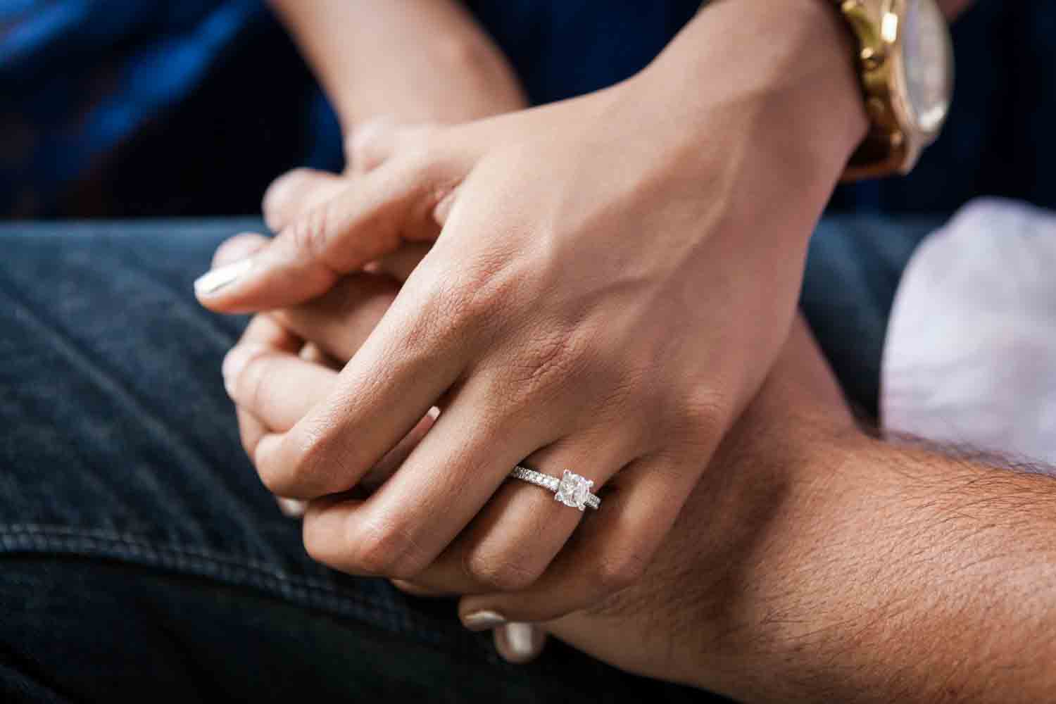 Close up on couple holding hand and woman wearing engagement ring