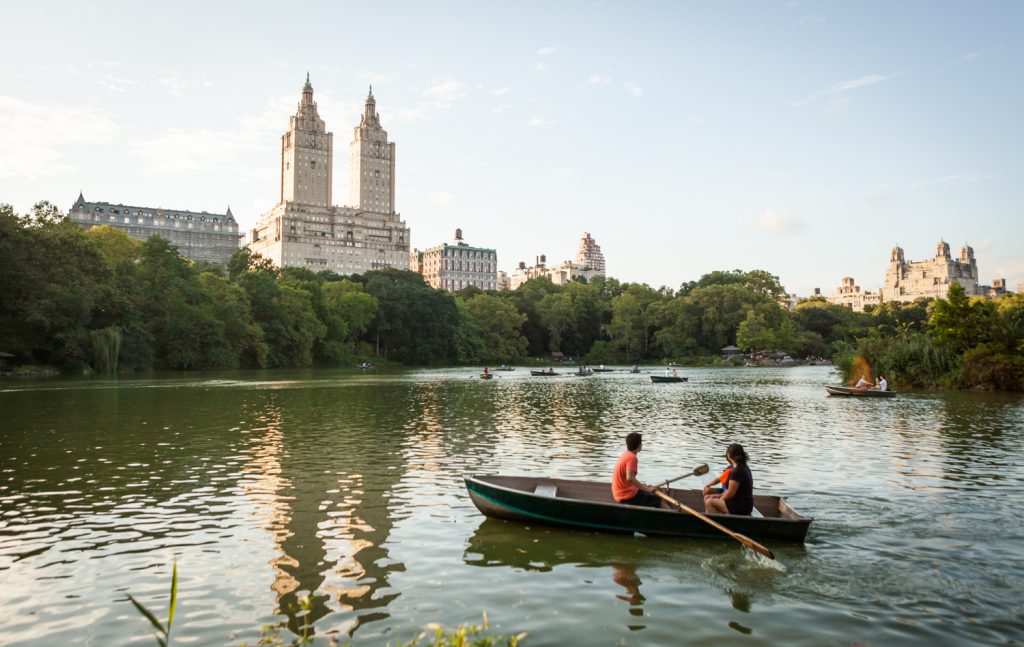 Couple in rowboat on Central Park lake with NYC skyline in background