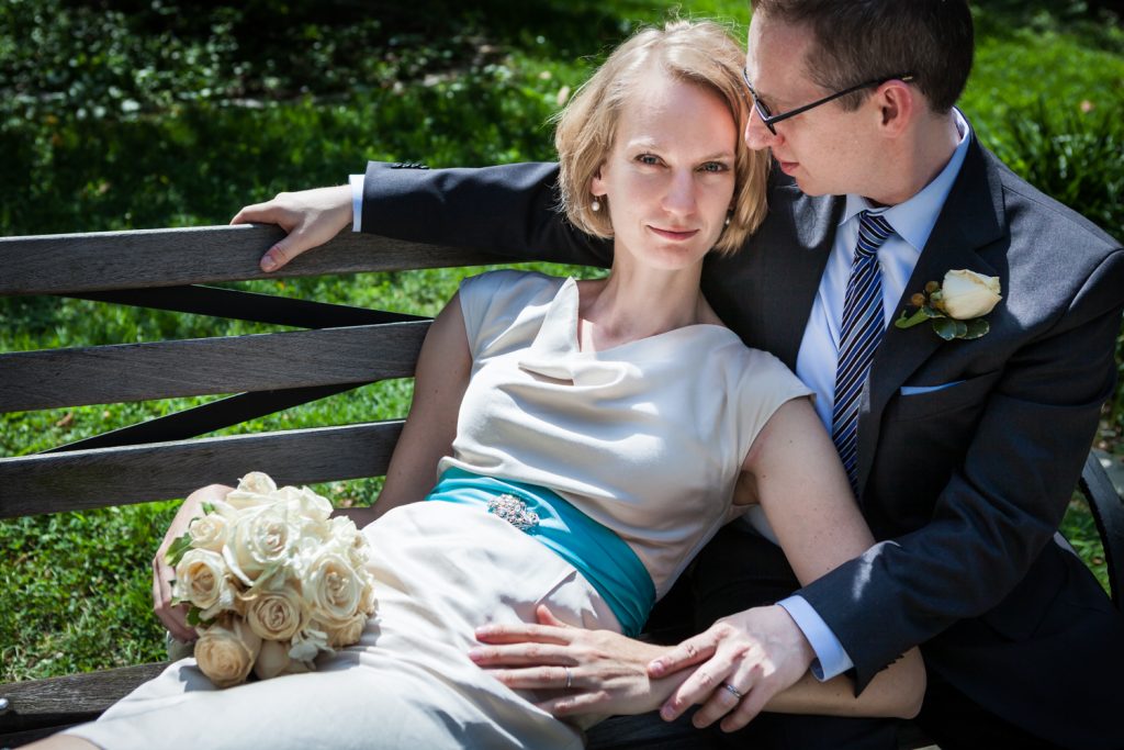 Bride with rose bouquet lounging in groom's lap