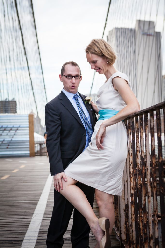 Bride and groom posed against railing on Brooklyn Bridge