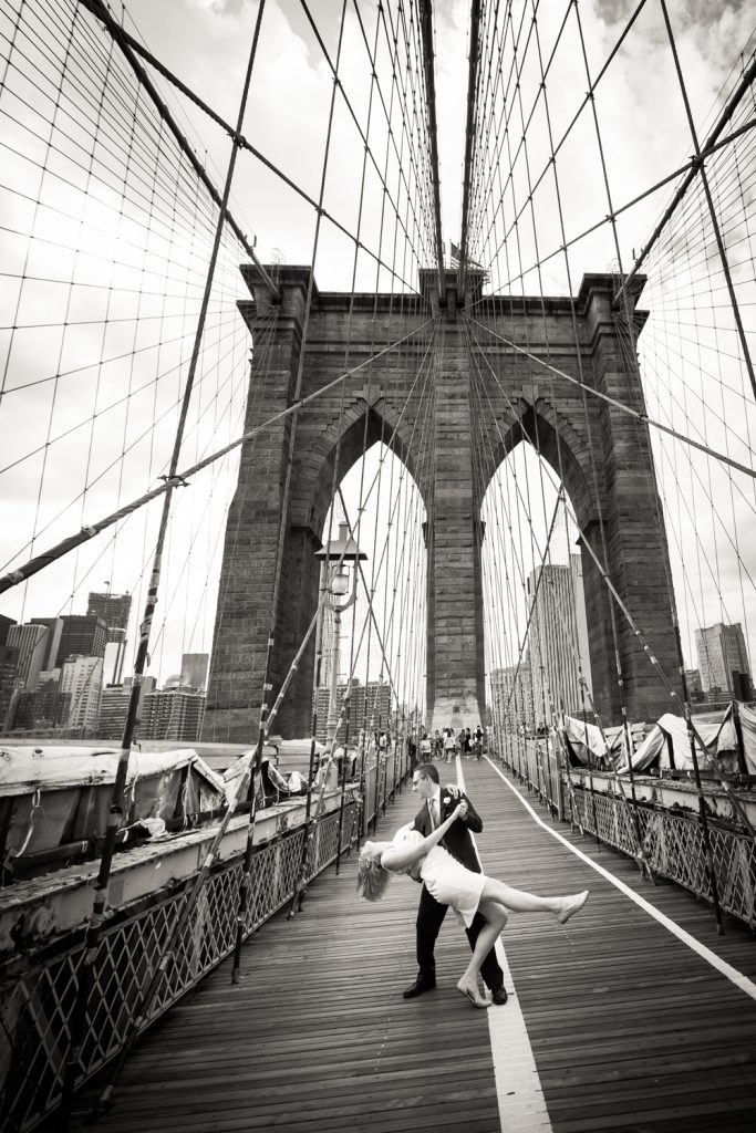 Black and white photo of bride and groom dancing on Brooklyn Bridge