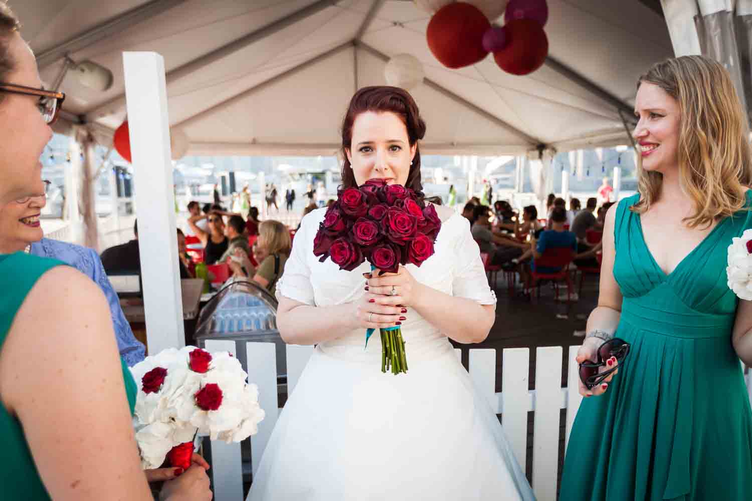 Bride with bouquet of roses between bridesmaids