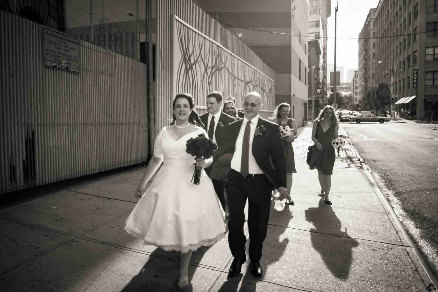 Black and white photo of bridal party walking on sidewalk