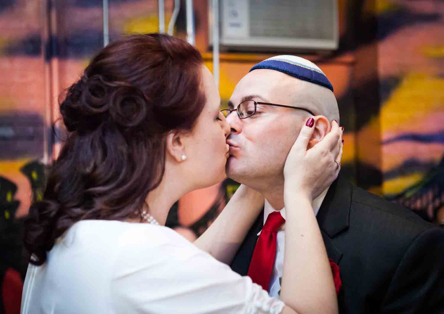 Bride holding groom's face and kissing him at a DUMBO wedding