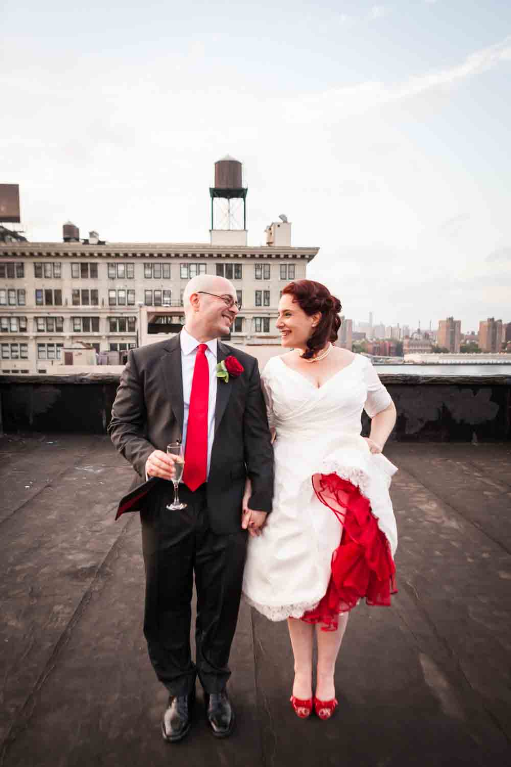Bride and groom jumping on rooftop at a DUMBO wedding