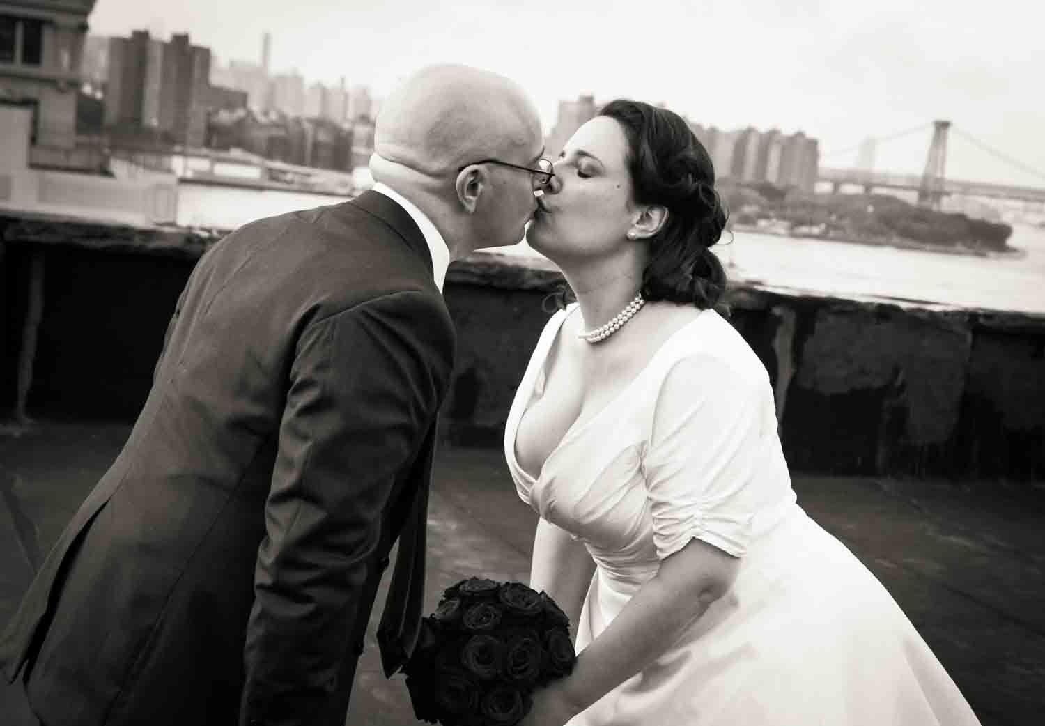 Black and white photo of bride kissing groom at a DUMBO wedding
