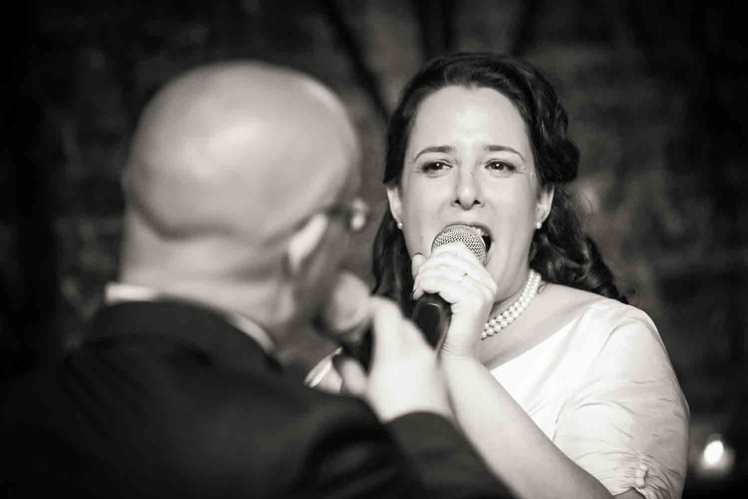 Black and white photo of bride and groom singing to each other