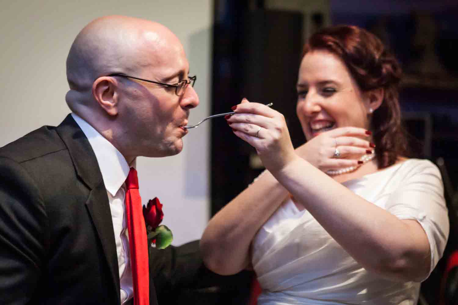Bride feeding cake to groom at a DUMBO wedding