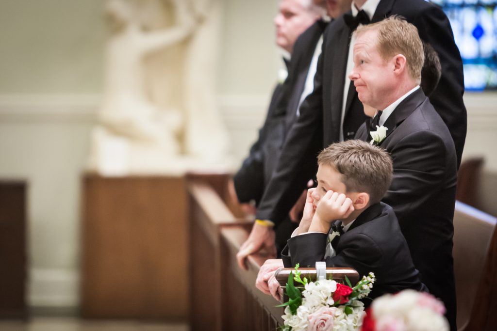 Young ring bearer holding head in hands during St. Peter's Church wedding ceremony