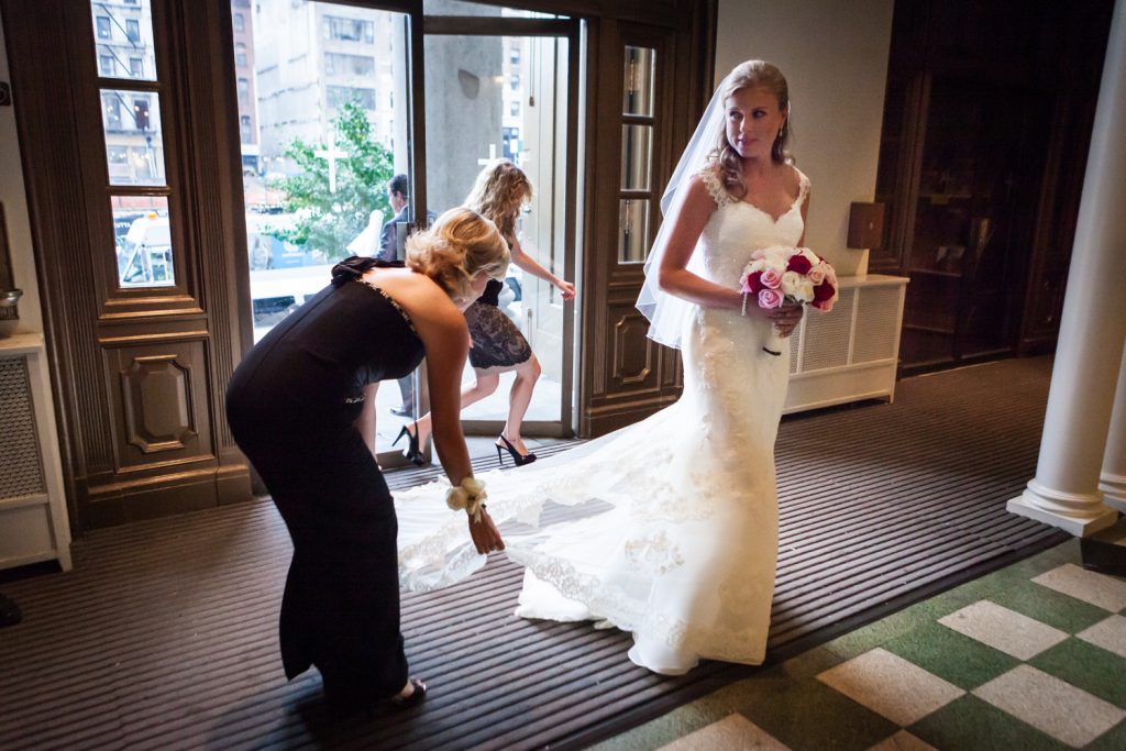 Bridesmaids fixing bride's train before she enters St. Peter's Church