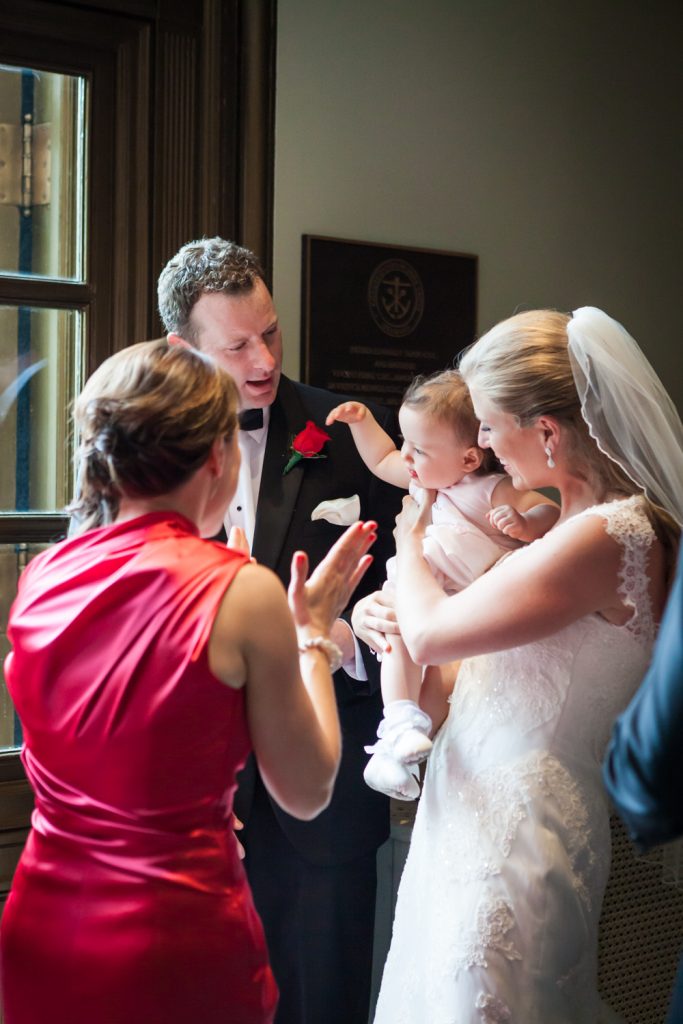 Bride and groom playing with baby after St. Peter's Church wedding ceremony