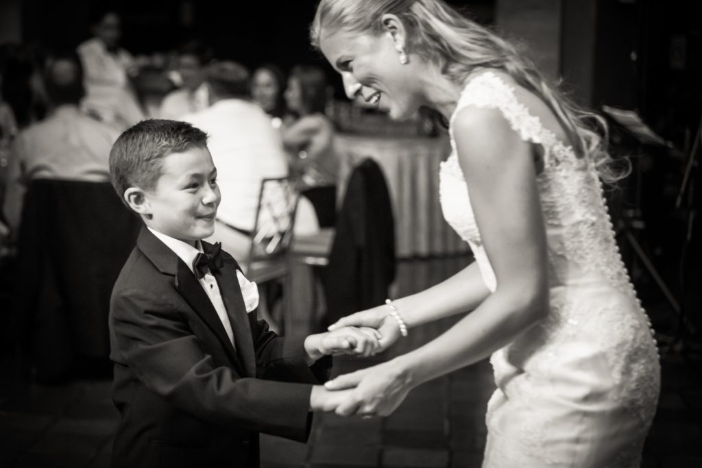 Black and white photo of bride dancing with young boy