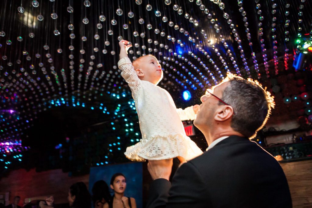 Baby reaching up for glittery ceiling at a bar mitzvah