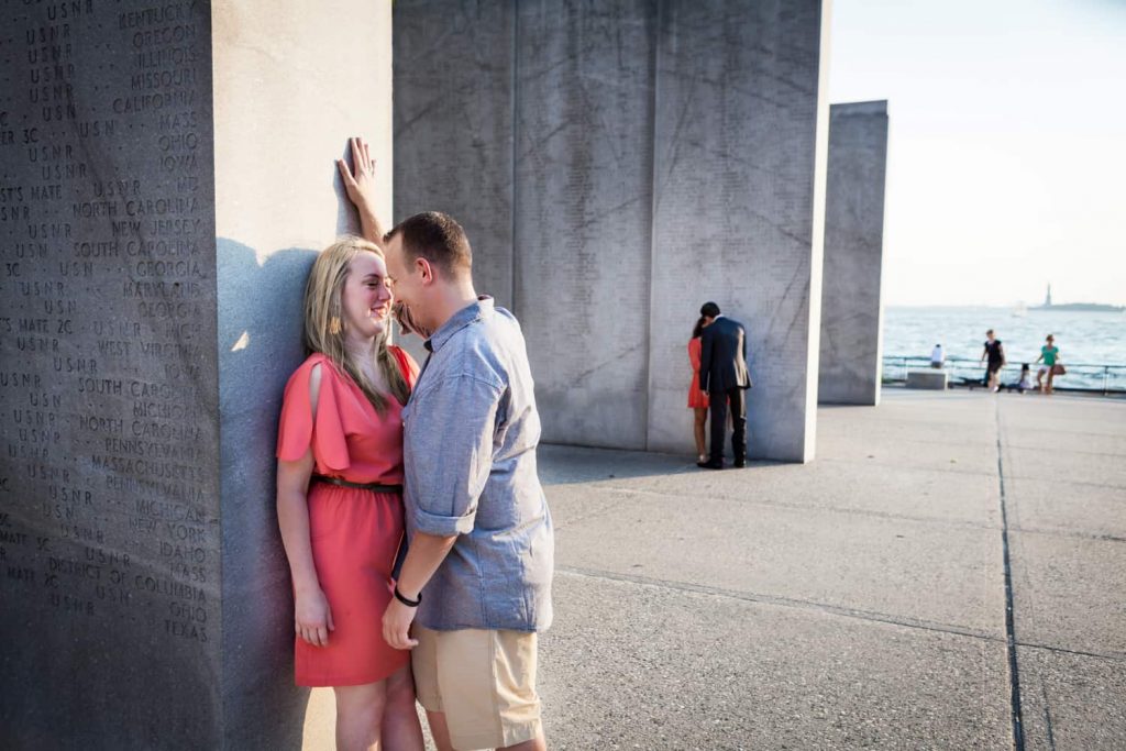 Couple leaning against concrete monument at a Battery Park engagement shoot