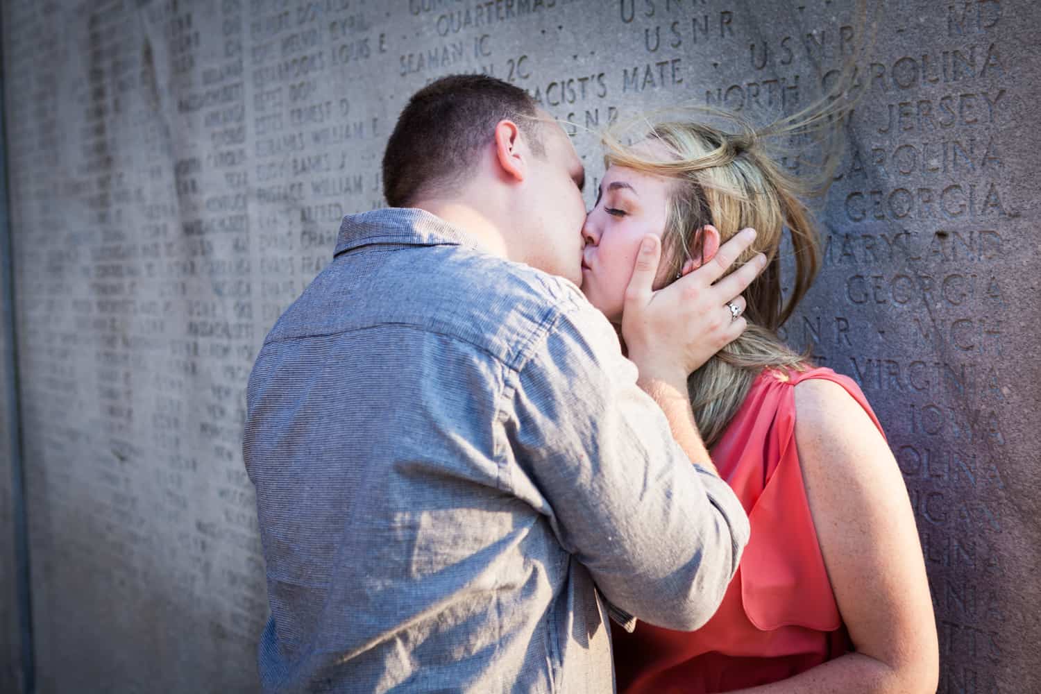 Couple kissing against concrete monument at a Battery Park engagement shoot