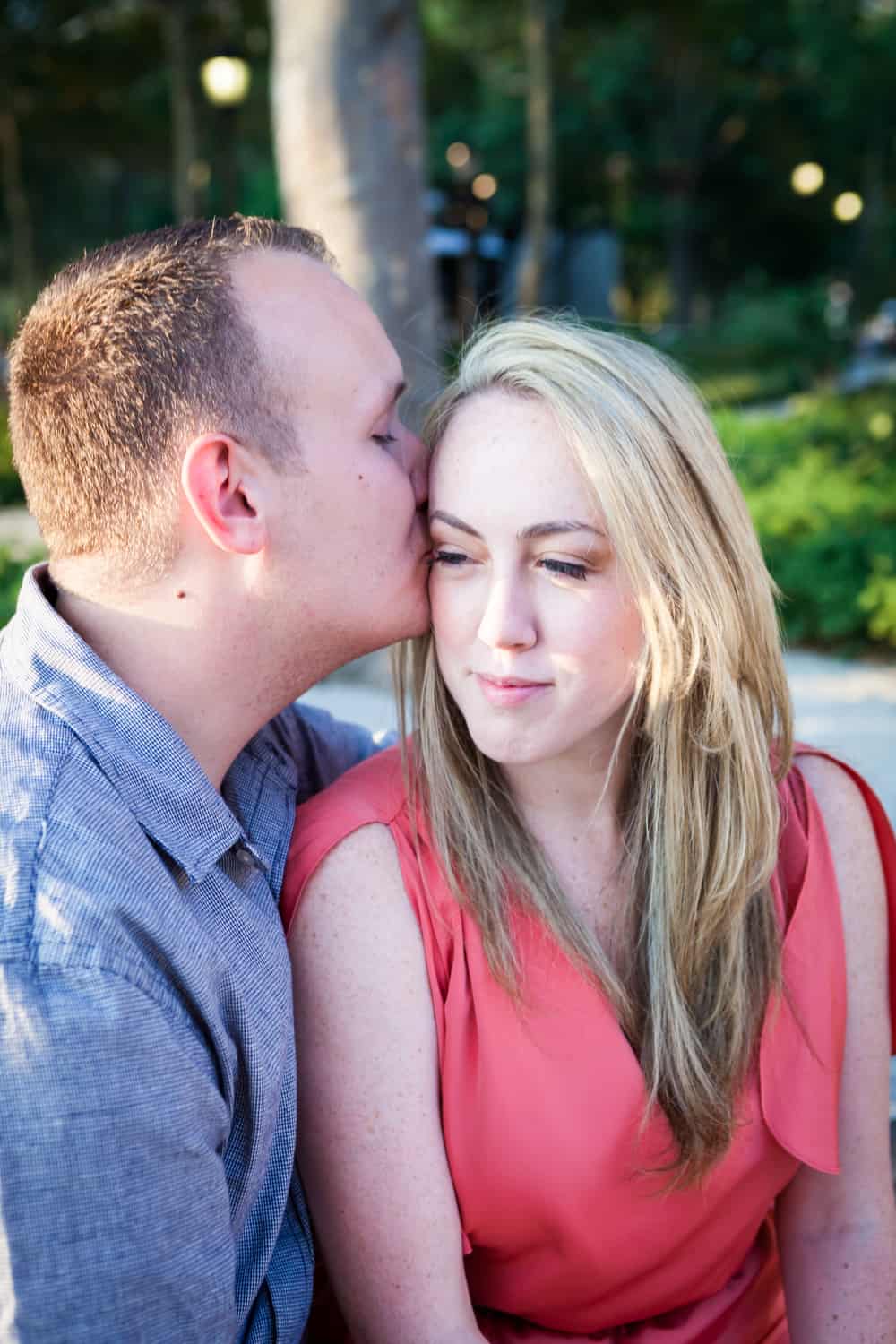 Man kissing woman on the side of head at a Battery Park engagement shoot