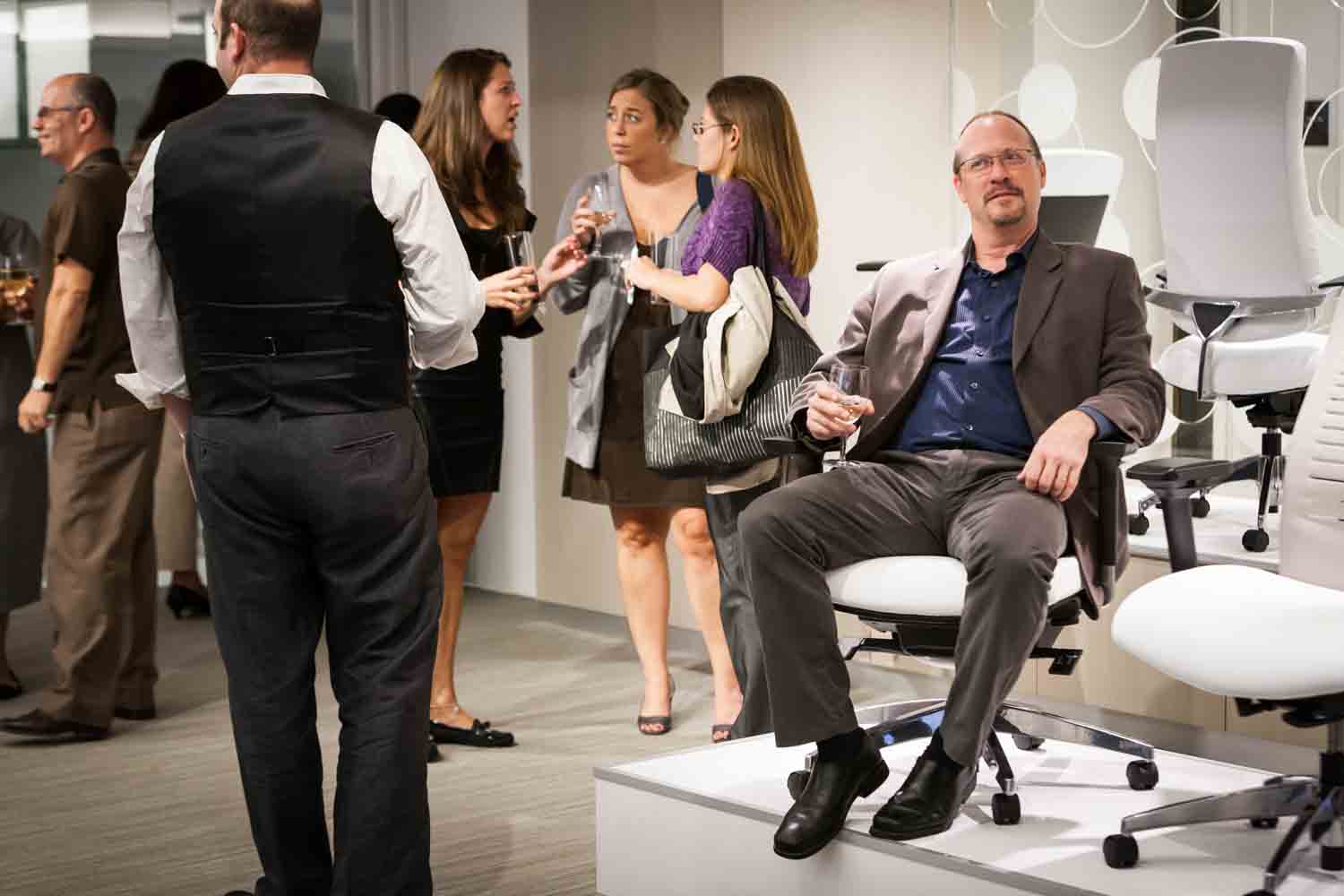 Guest seated in chair on display during corporate cocktail party
