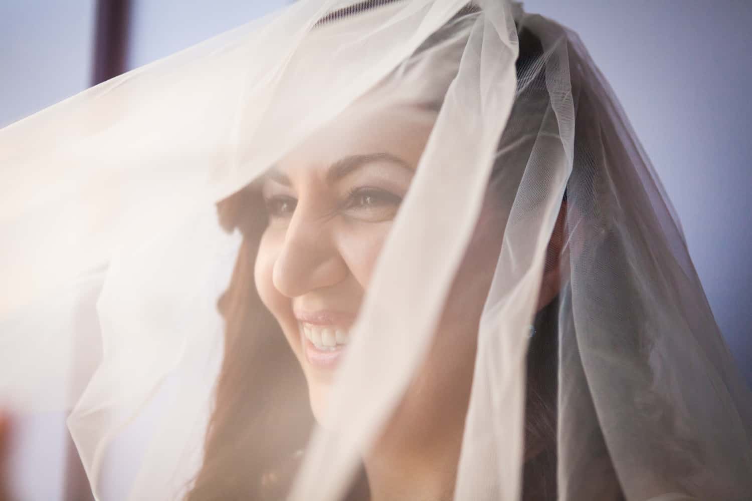 Bride laughing under veil