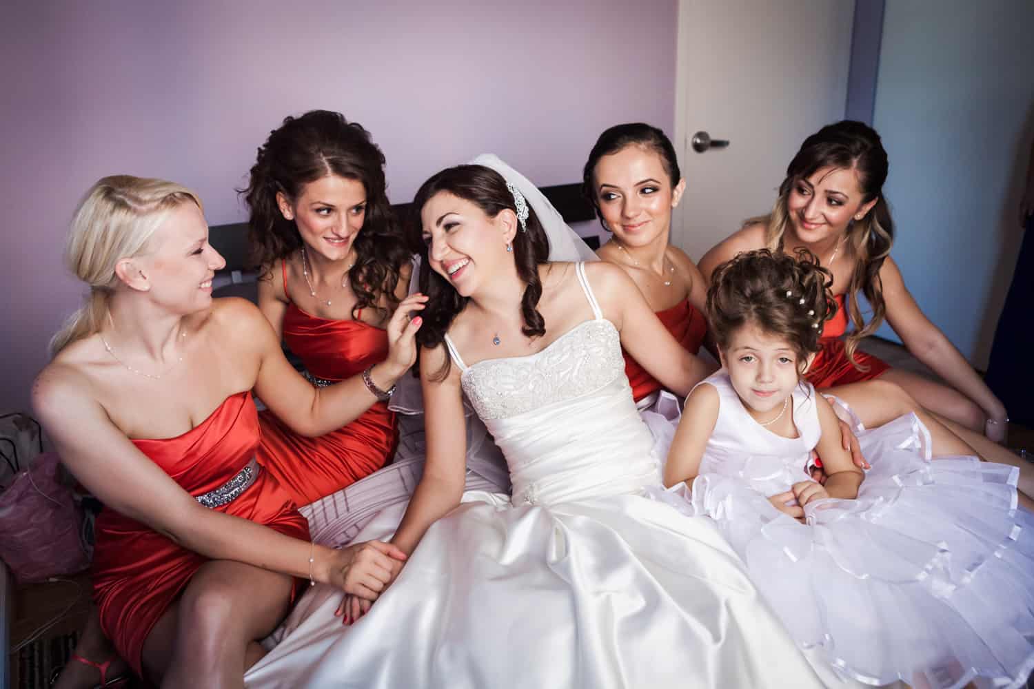 Bride and bridesmaids laughing on bed