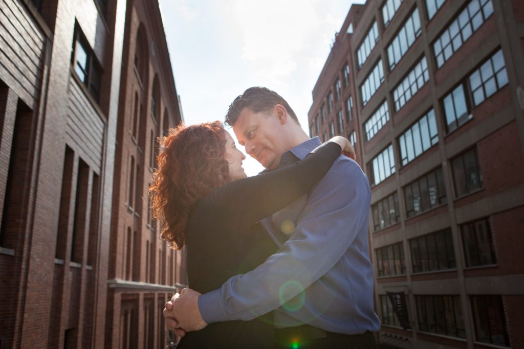 High Line engagement photos of couple looking at each other with factory in background