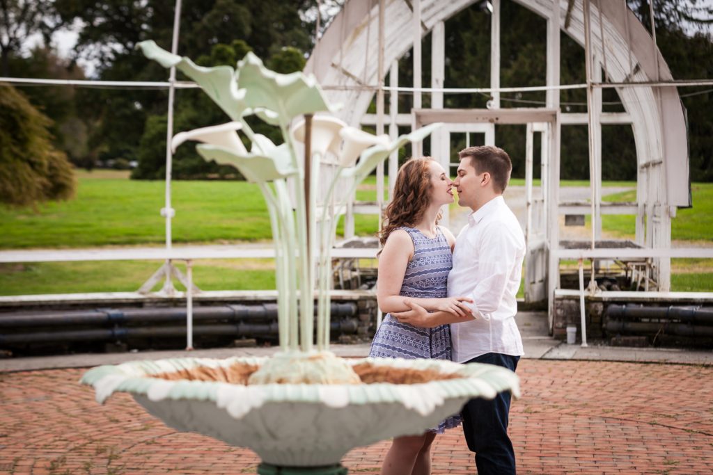 Couple kissing behind elaborate fountain at a Lyndhurst Mansion engagement photoshoot