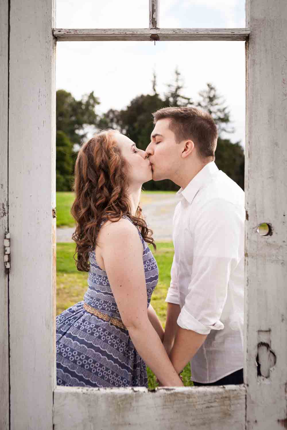 View of couple kissing through door at a Lyndhurst Mansion engagement photoshoot