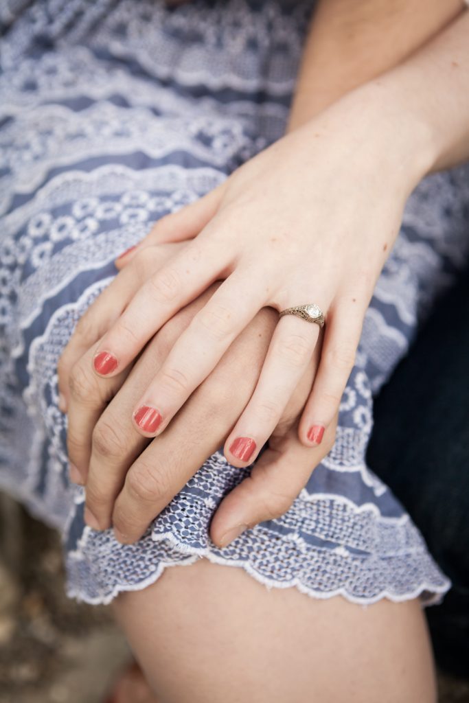 Close up on couple's hands with woman wearing engagement ring