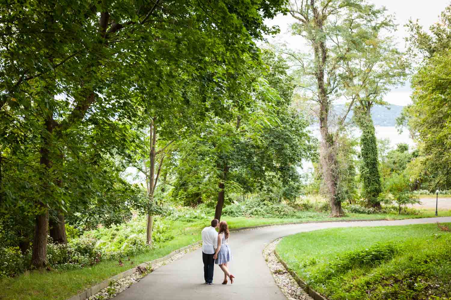 Wide shot of couple walking down pathway at Lyndhurst Mansion garden