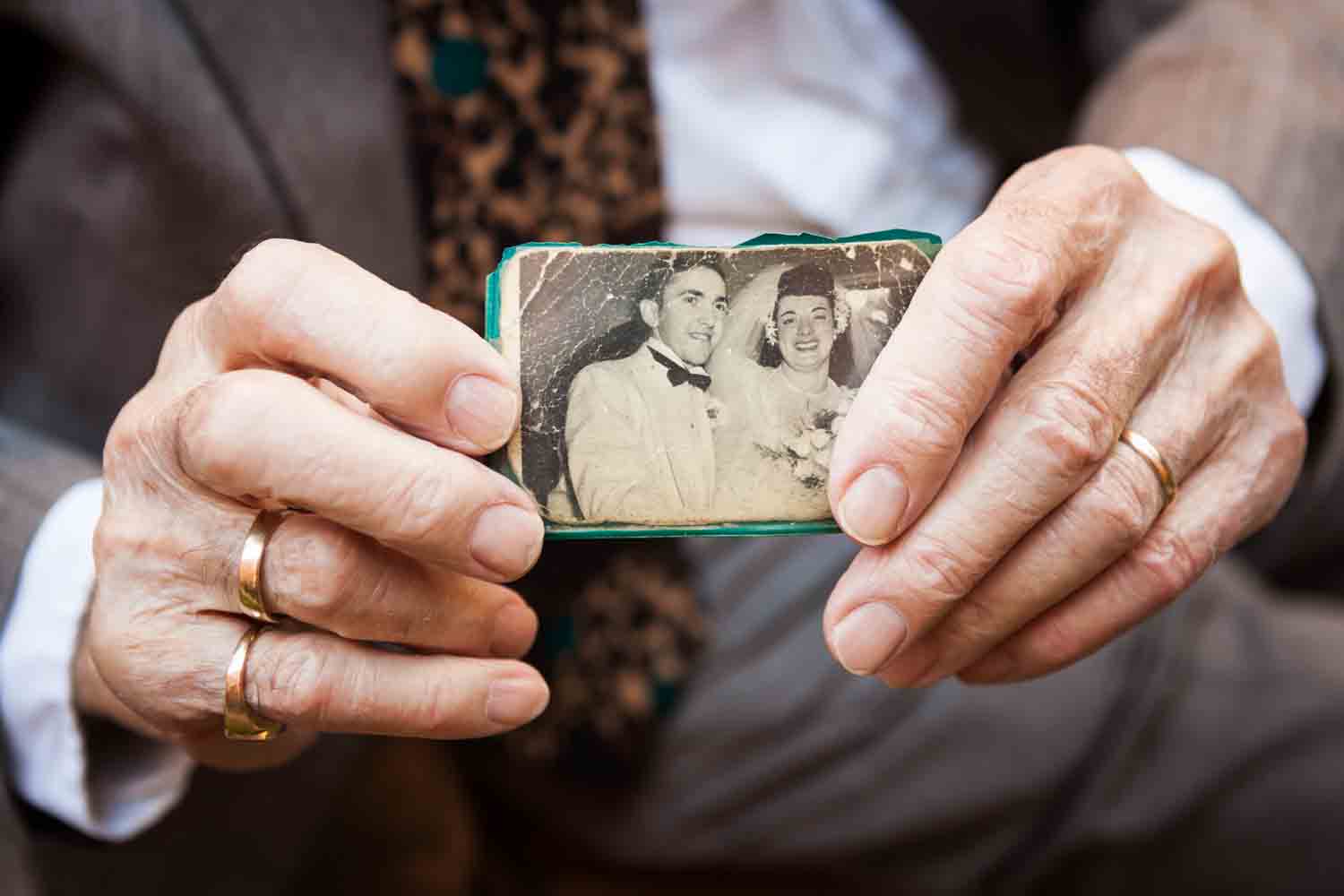 Close up on grandfather's hands holding black and white wedding portrait