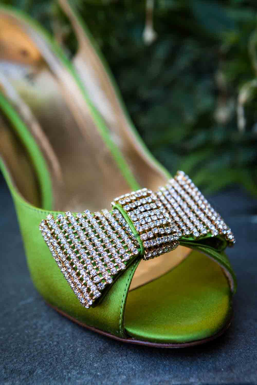 Close up on green satin high heel with diamond bow