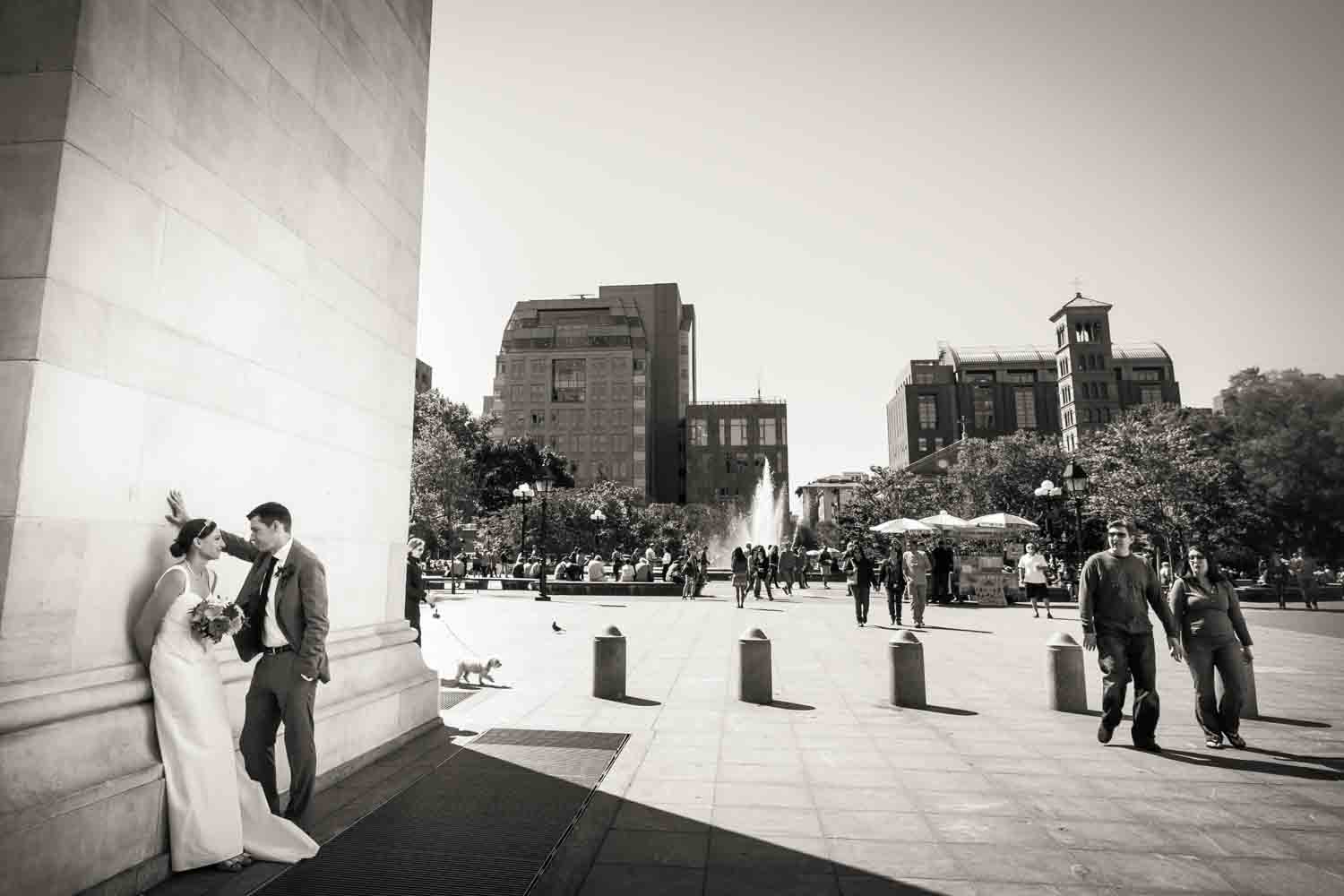 Bride and groom standing against Washington Square Park arch