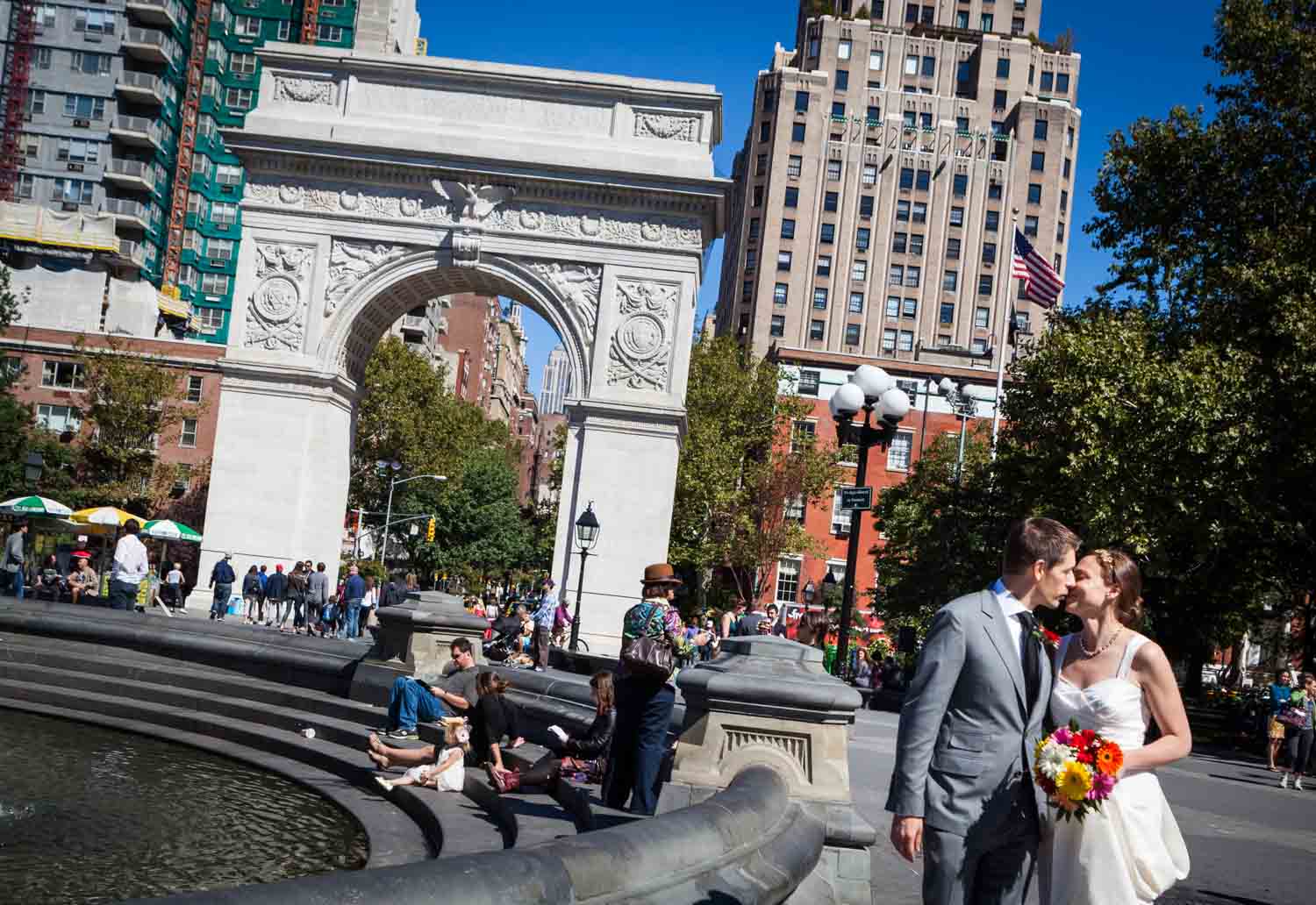 Bride and groom kissing with Washington Square Park arch in background
