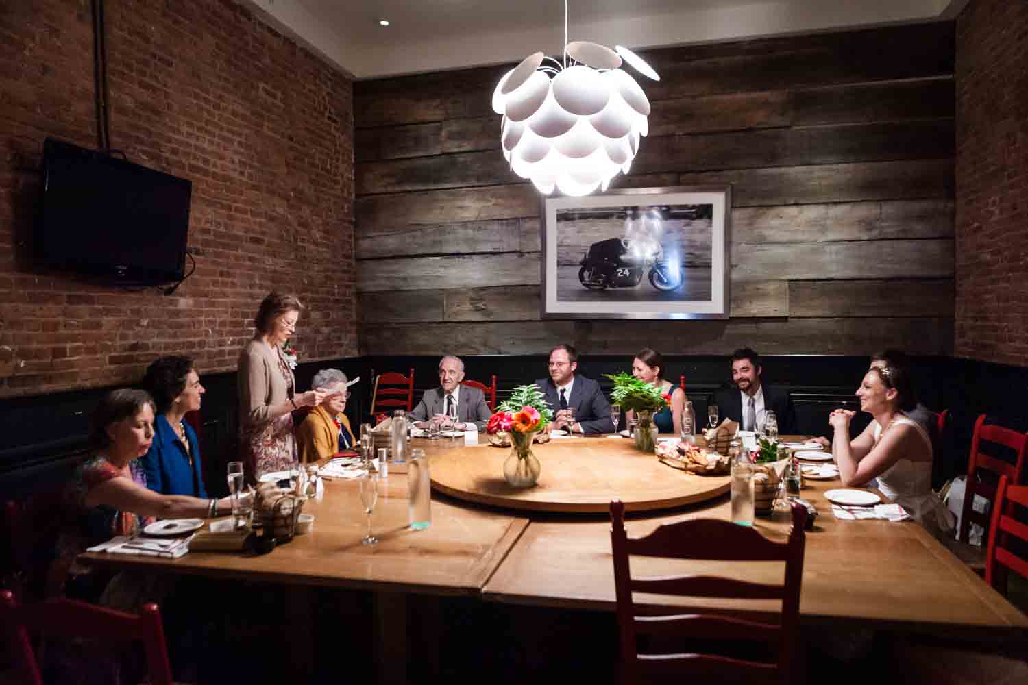 Wide shot of people seated around wooden table at Tribeca reception