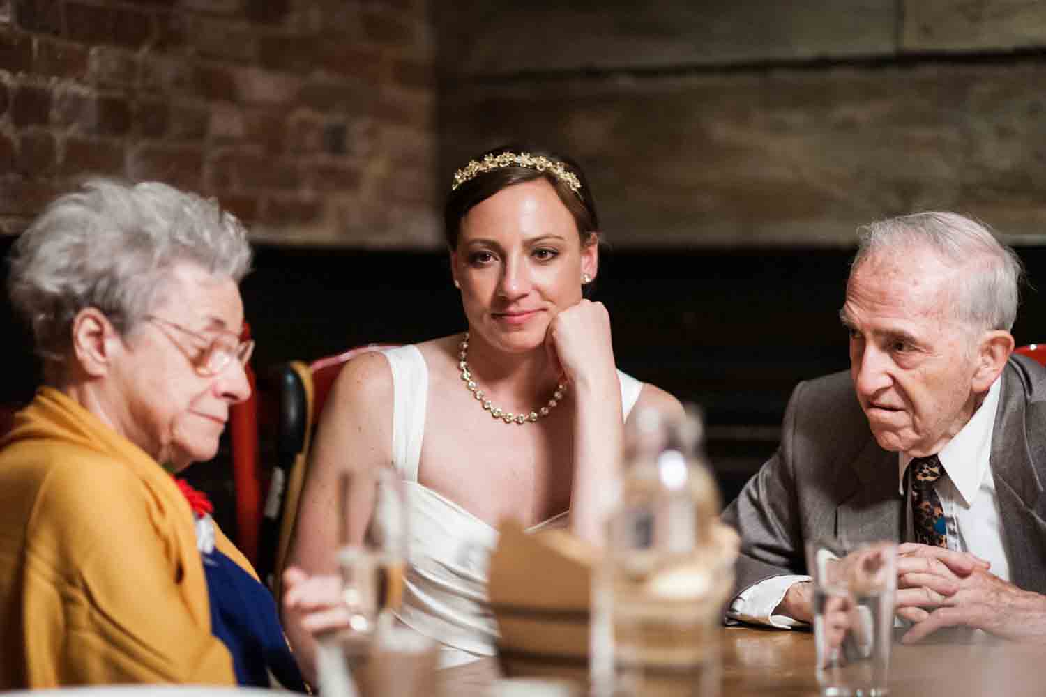 Bride sitting in between her grandparents at Tribeca reception
