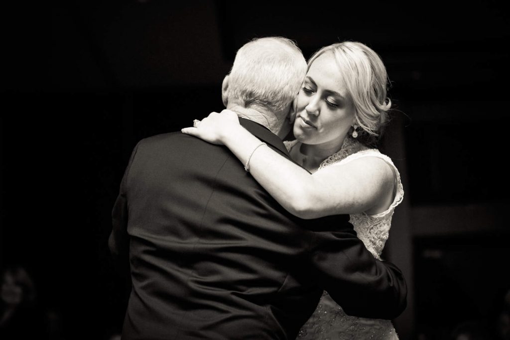 Black and white photo of bride dancing with father