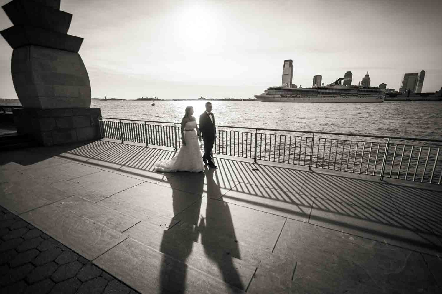 Black and white photo of bride and groom walking in Rockefeller Park