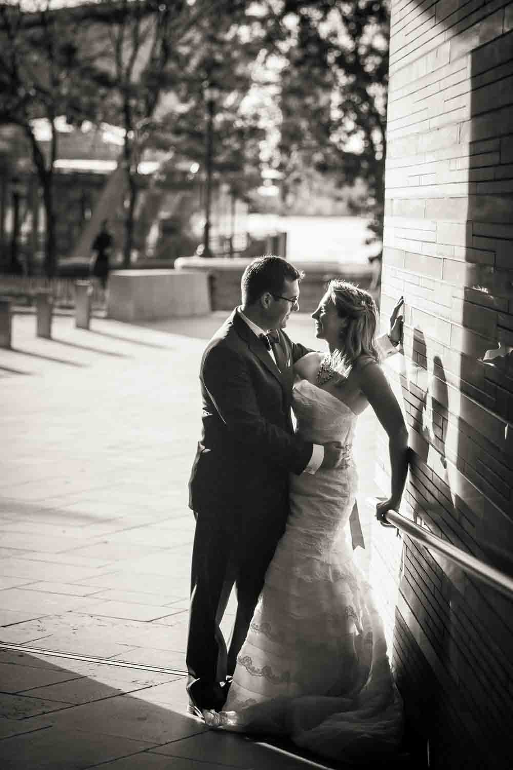 Black and white photo of groom and bride against wall