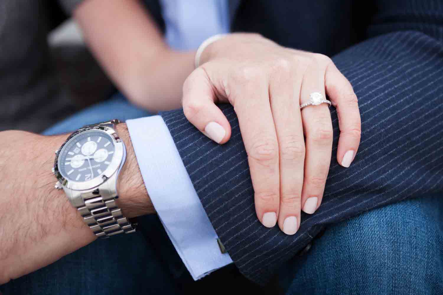 Close up of woman's hand wearing engagement ring on man's arm