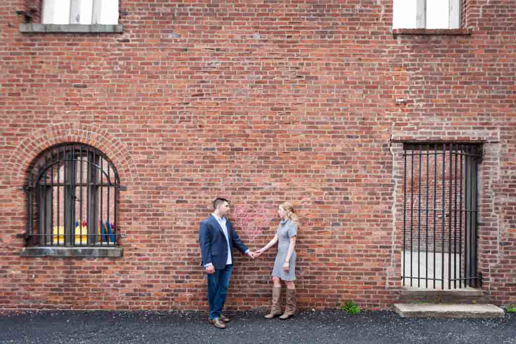 Couple holding hands against brick wall