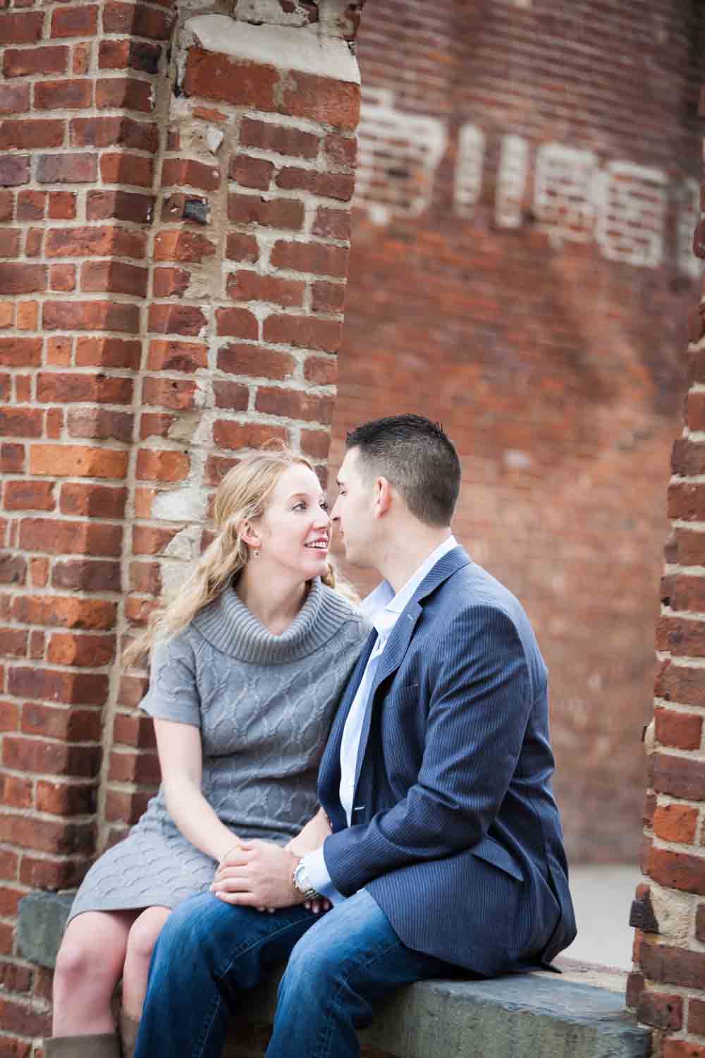 Couple kissing in brick archway during a Brooklyn Bridge Park engagement shoot